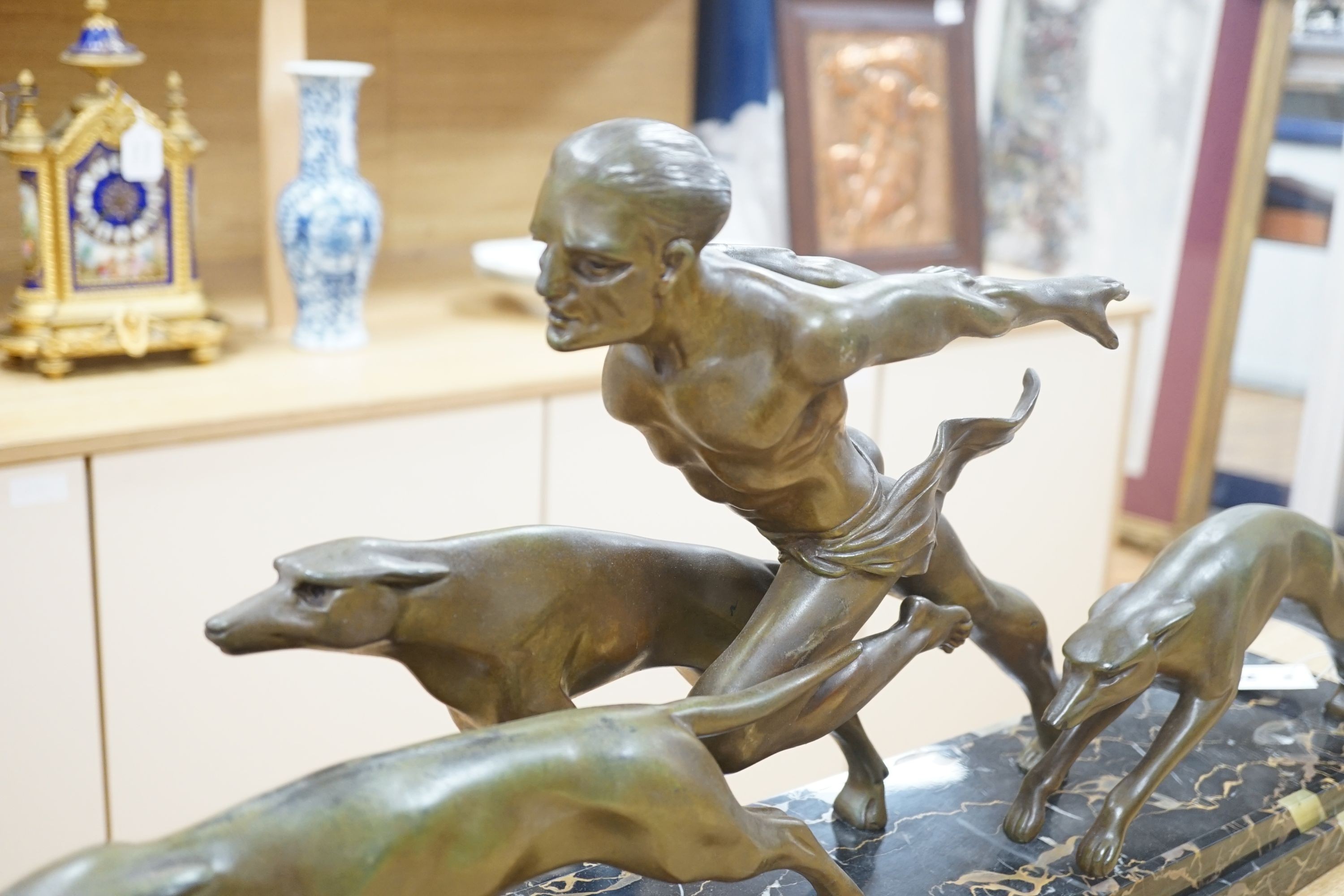 An Art Deco bronzed metal and marble running man with greyhounds, signed L Valderi, 85cm long